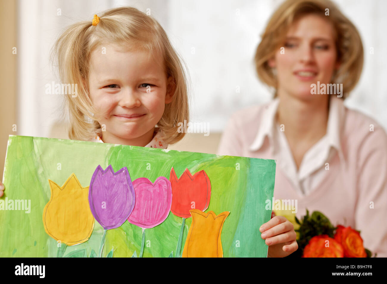 Mother happily daughter picture myself-painted holding portrait Stock Photo