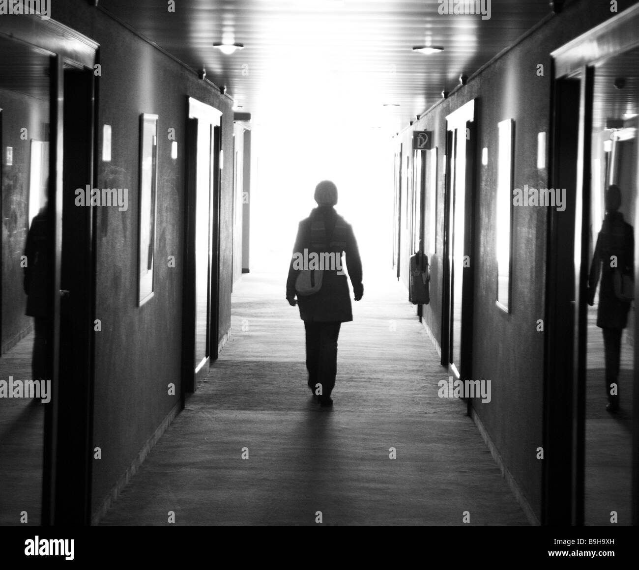 Hotel-halls woman movement back view back light s/w buildings stairwell hall people person winter-clothing jacket scarf cap Stock Photo