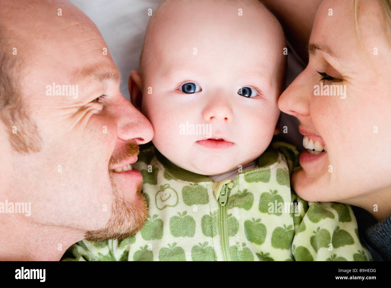 Baby laying between dad and mom Stock Photo - Alamy