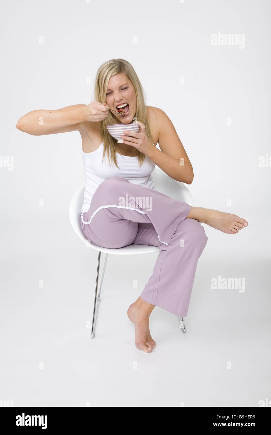 woman young cozy chair sitting muesli eating series people 30-40 years blond long-haired stout overweight jogging pants Stock Photo