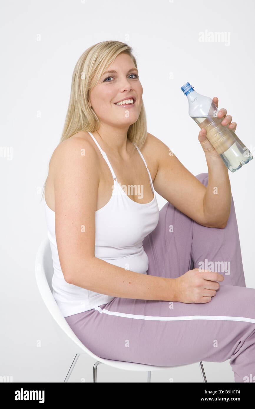 woman young cozy chair sitting bottle drinks series people 30-40 years blond long-haired stout overweight jogging pants Stock Photo