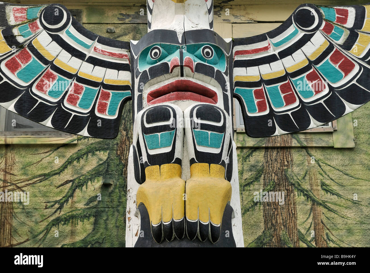 Totem pole of the Cowichan Indians, close-up, in front of a painted house wall, Duncan, Vancouver Island, Canada, North America Stock Photo