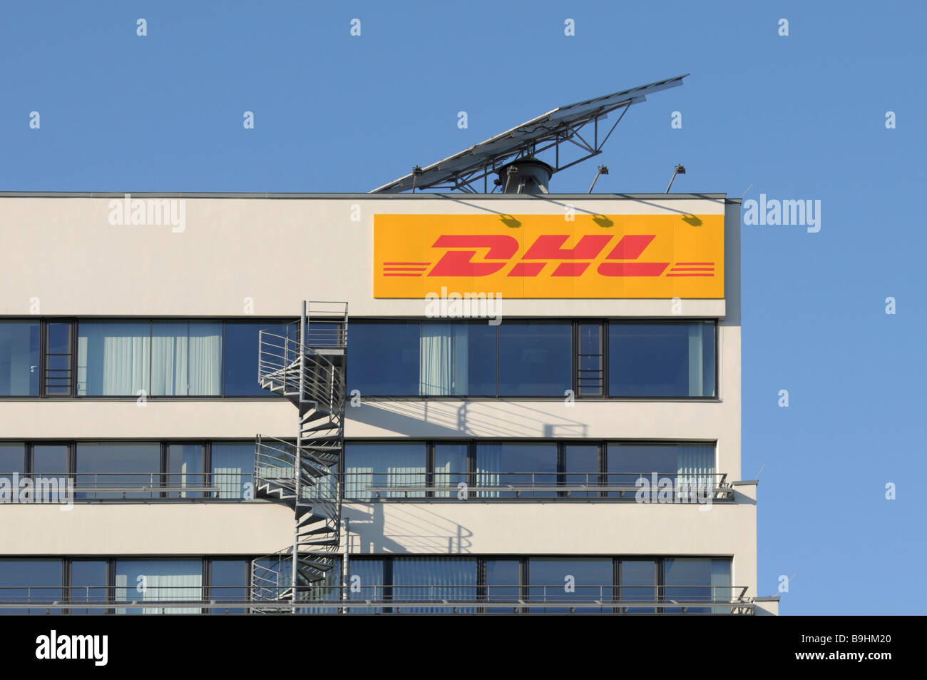 DHL logo on an office building, above it a mobile solar module, built-on fire stairs Stock Photo