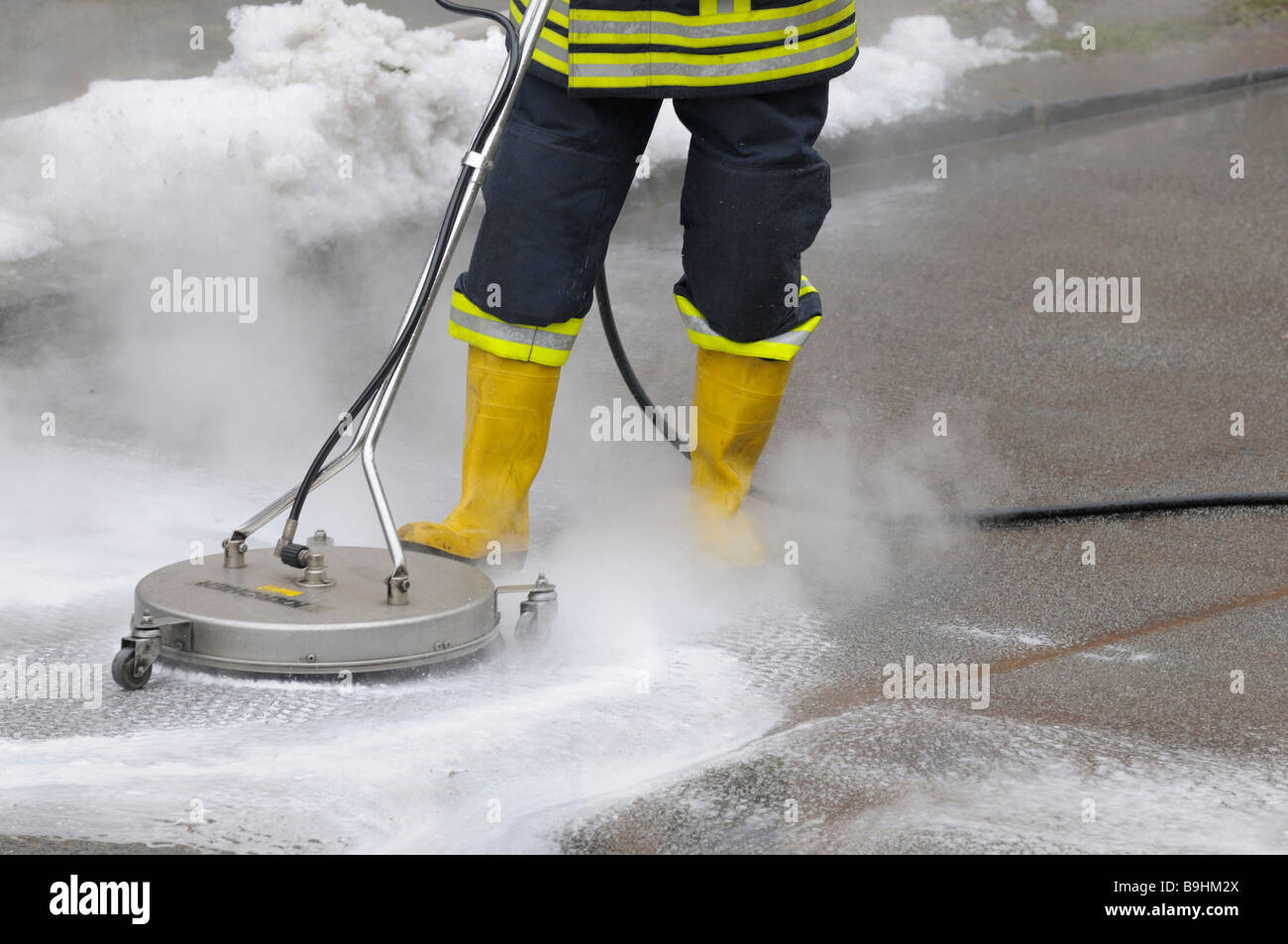 Fireman neutralising leaked brake fluid from a street with cleaning