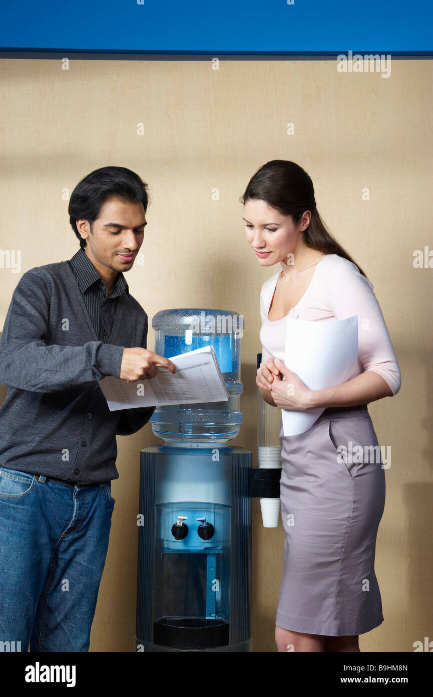 Man and woman standing by water cooler Stock Photo