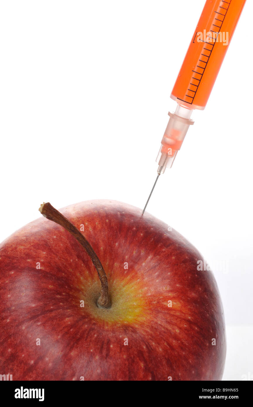 Syringe in an apple, symbolic for genetically manipulated foods Stock Photo