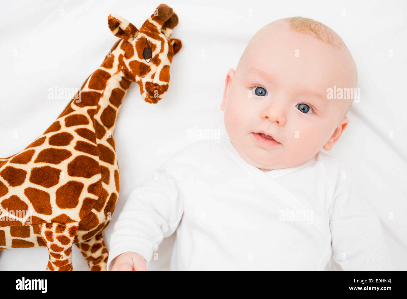 Baby laying next to a plush giraffe Stock Photo