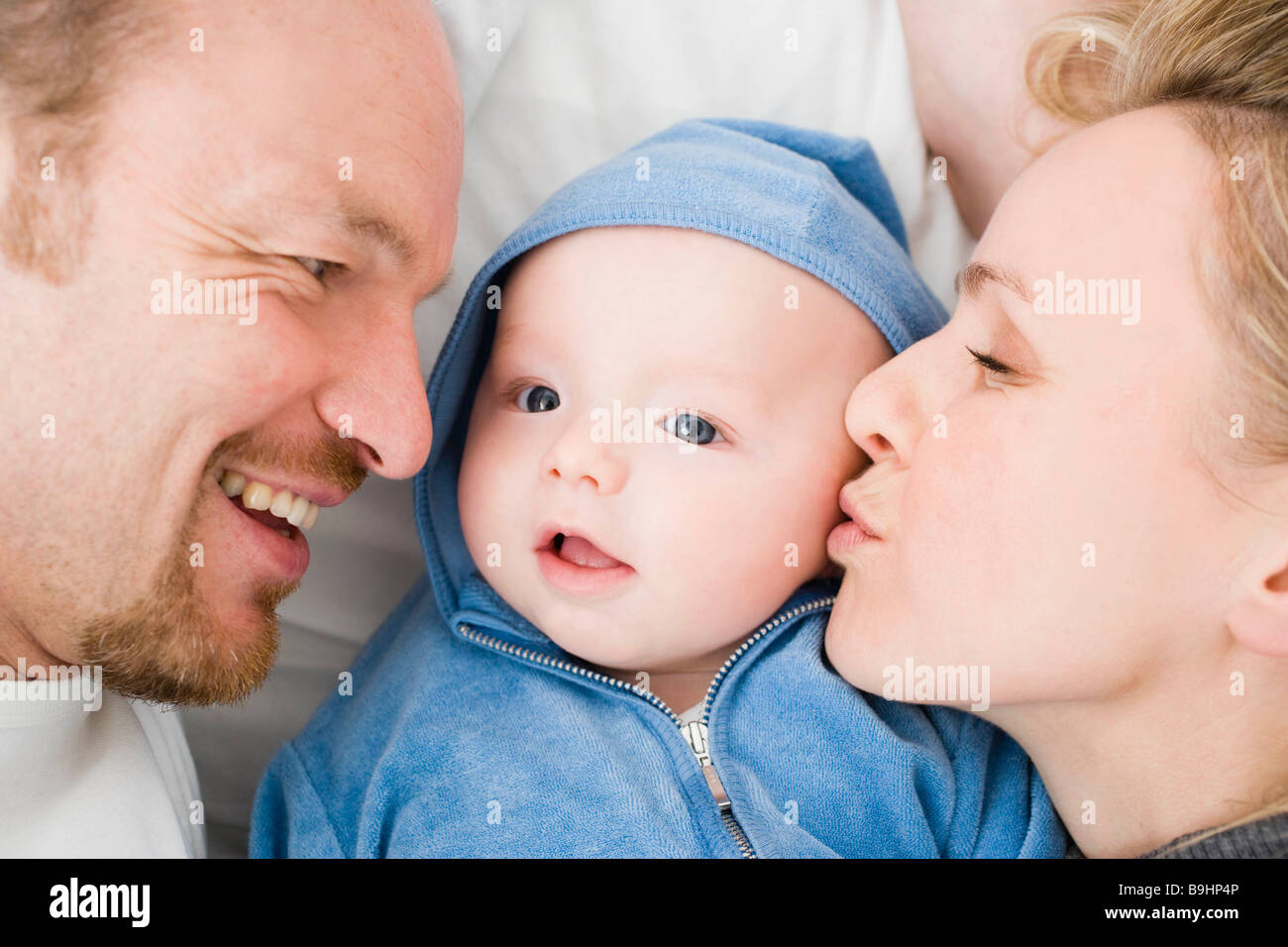 Baby laying between dad and mom Stock Photo Alamy