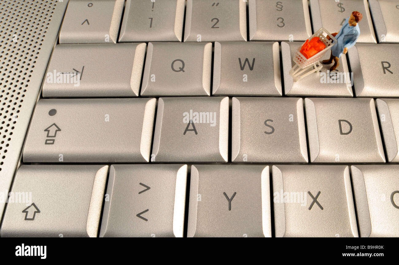 Miniature figurine pushing a shopping cart on an Apple MacBook Pro keyboard, symbol for online shopping Stock Photo