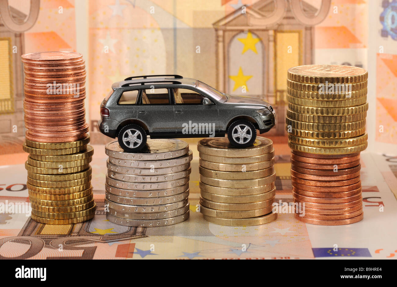 Miniature car on coins, symbolic of commuter tax allowance, mileage allowance, car maintenance Stock Photo