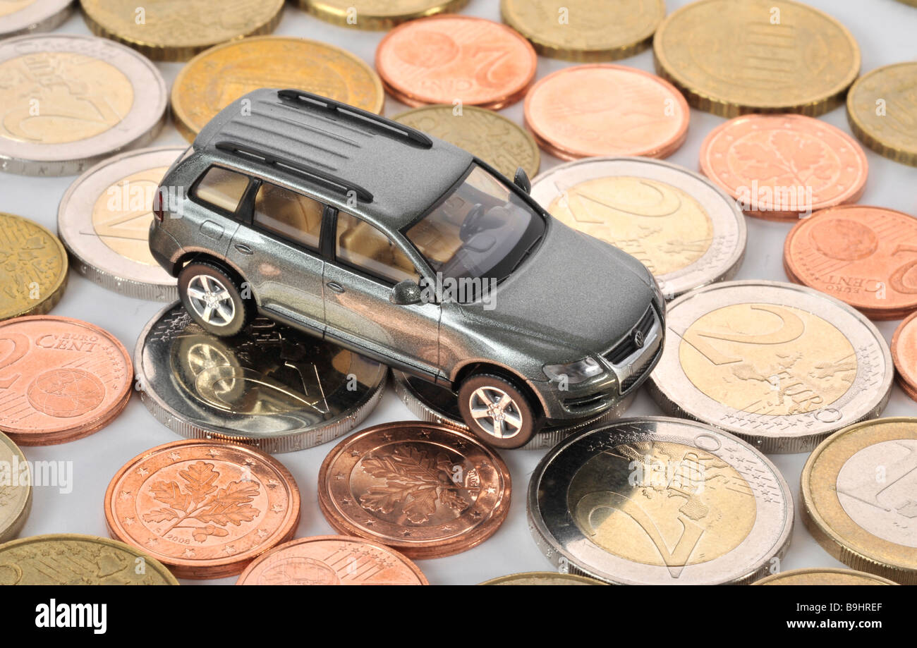 Miniature car on coins, symbolic of commuter tax allowance, mileage allowance, car maintenance Stock Photo