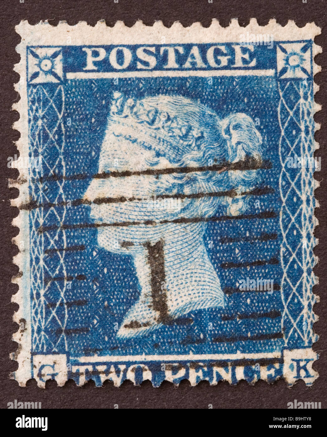 Close up of 2d blue Victorian British Postal stamp on black background. Used with postmark, issued between 1854-57. Stock Photo