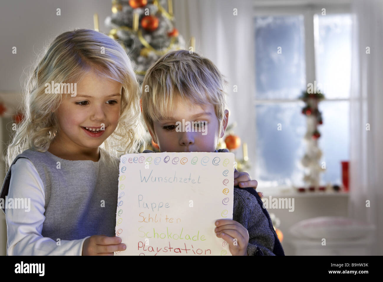 Christmas children wish lists reading semi-portrait series people childhood 4-6 years siblings girl boy blond smiling  holds Stock Photo