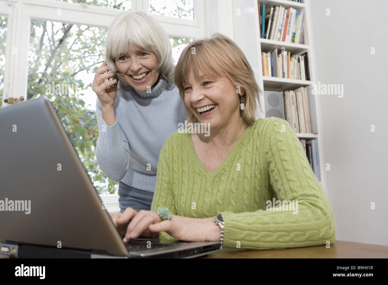 Seniors laptop data input laughs cell phone telephones detail series people seniors women two cheerfully computers data Stock Photo