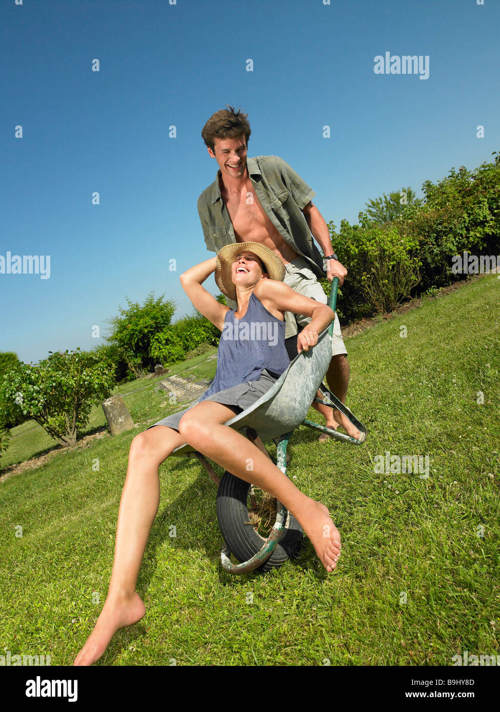 Man pushing woman in a wheelbarrow Stock Photo