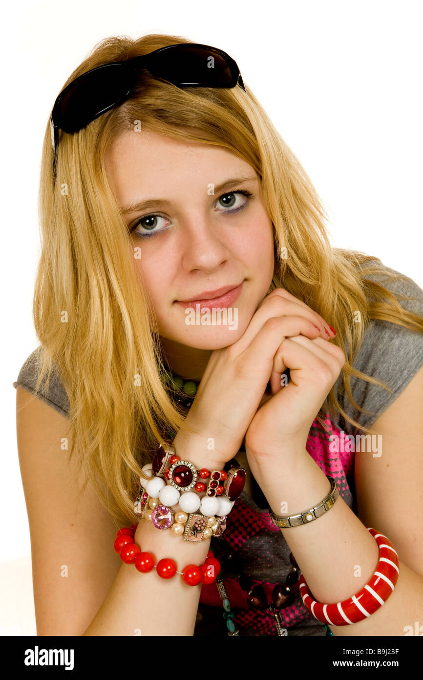 Portrait of a 13-year-old girl wearing a lot of necklaces, bangles, sunglasses pushed up on her head, smiling Stock Photo