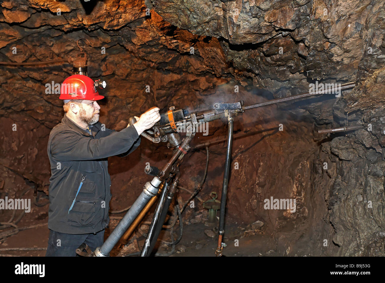 Miner demonstrating a compressed air rock drill in an adit, disused ore mine, Buechenberg mining museum, Elbingerode, Harz, Sax Stock Photo