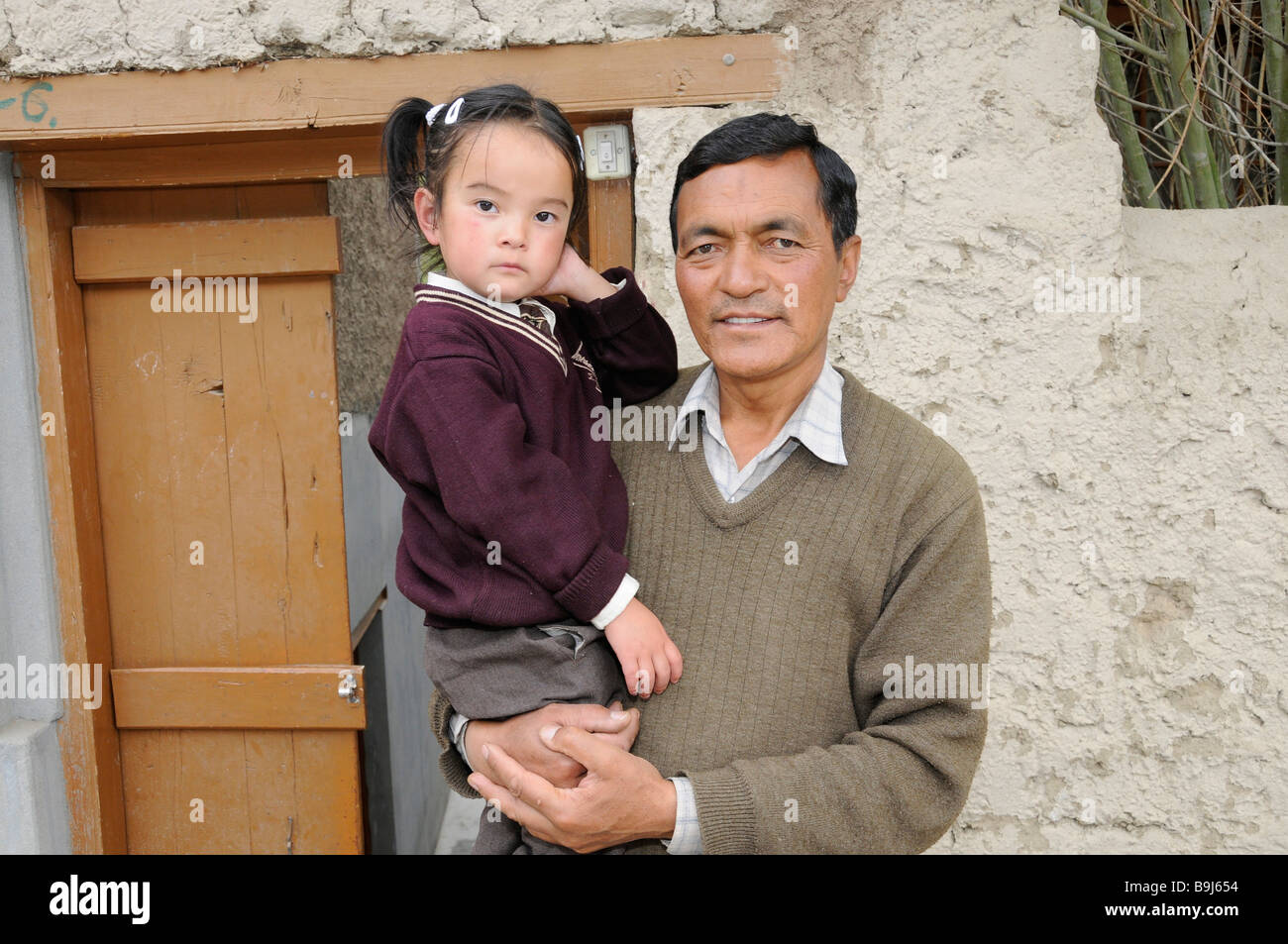 Ladakhi with daughter on his arm in front of his house, Leh, Ladakh, North India, Himalaya, Asia Stock Photo