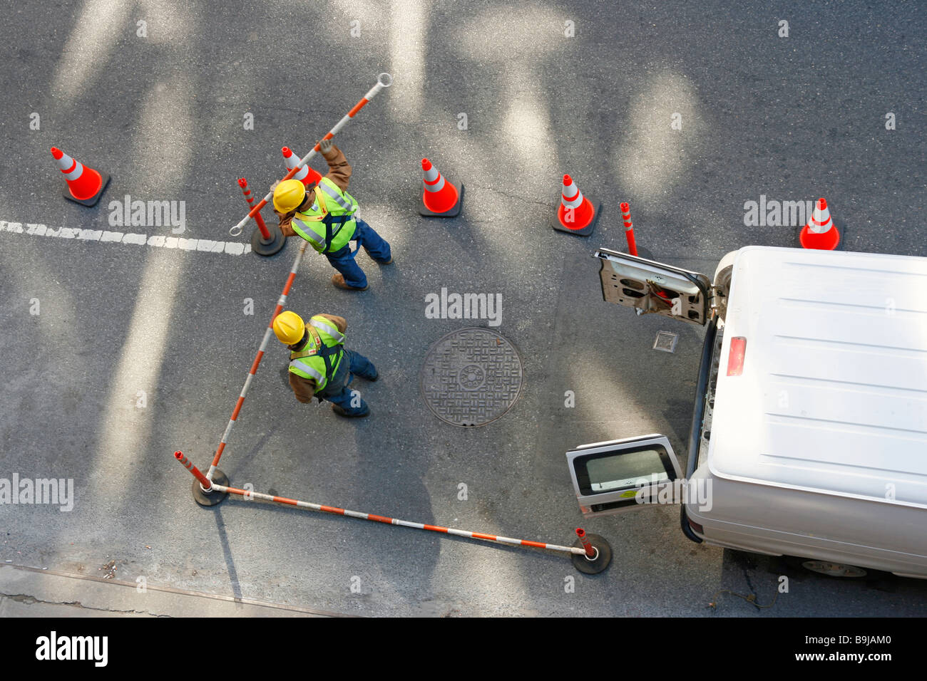 Street utility workers taking down barriers surrounding a manhole. Stock Photo