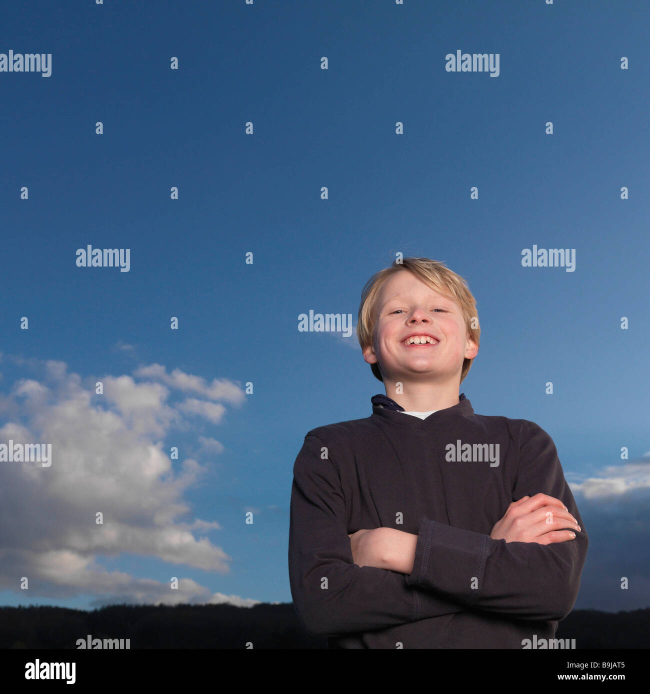 Boy standing with arms crossed, smiling Stock Photo