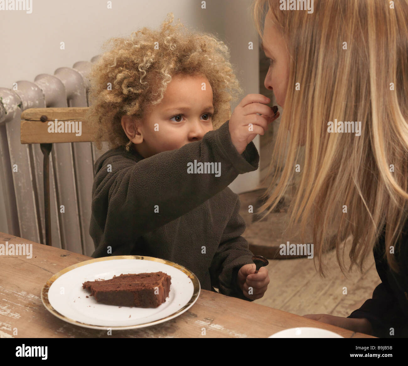 Young boy feeding cake to mother Stock Photo