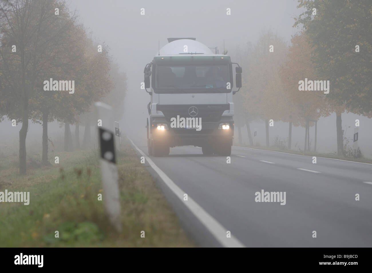 Truck driving with dimmed headlights on a country road in dense fog, Hesse, Germany, Europe Stock Photo