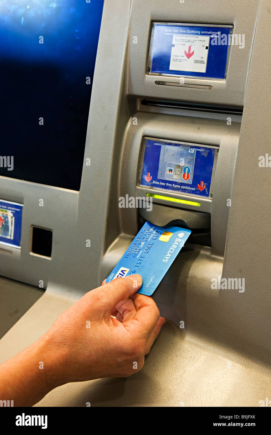 Inserting debit card into bank ATM Germany Stock Photo