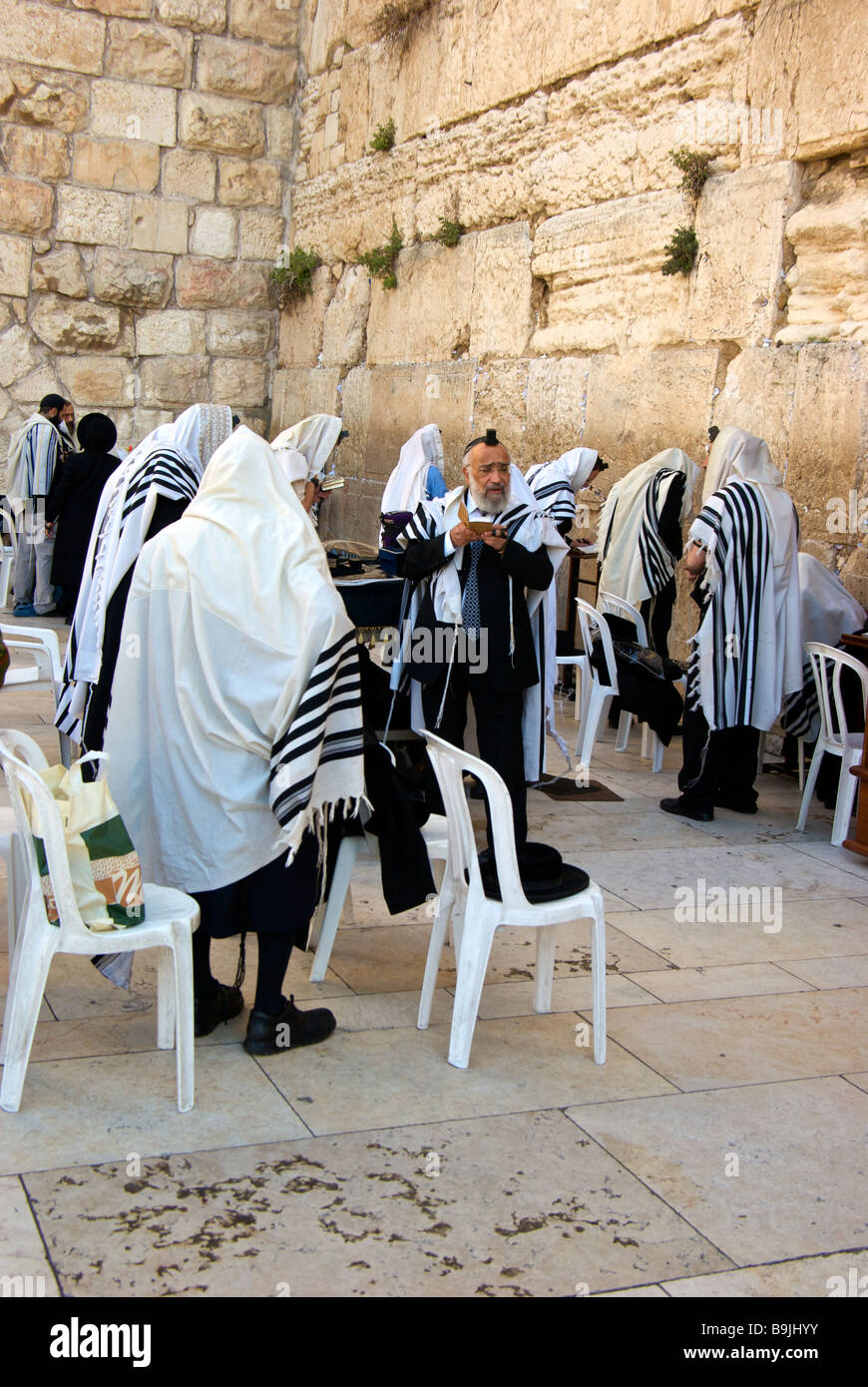 Devout Jewish men praying at exposed section of ancient Holy Western Wall of old Jerusalem Stock Photo