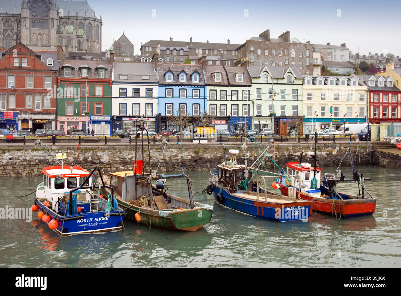 Fishing boats in Cobh harbour with the town and St. Colman's Cathedral in the background, County