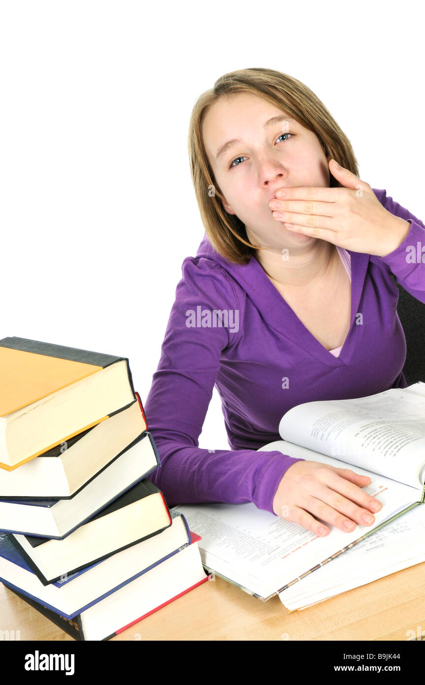 Yawning teenage girl studying at the desk Stock Photo
