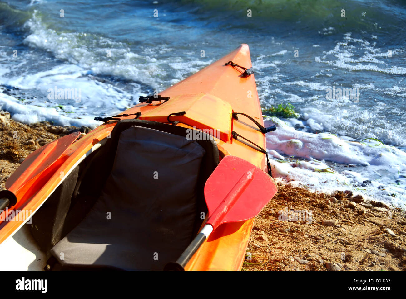 Orange kayak on a sandy shore of a river Stock Photo