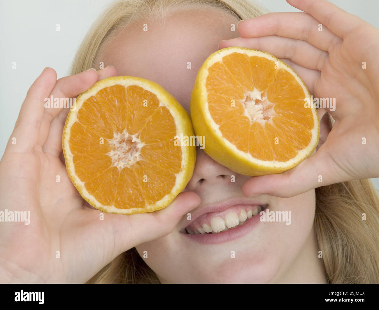 girl detail face oranges eyes lasts smiling series child blond long-haired face fruit fruit orange-disks disks vitamins health Stock Photo