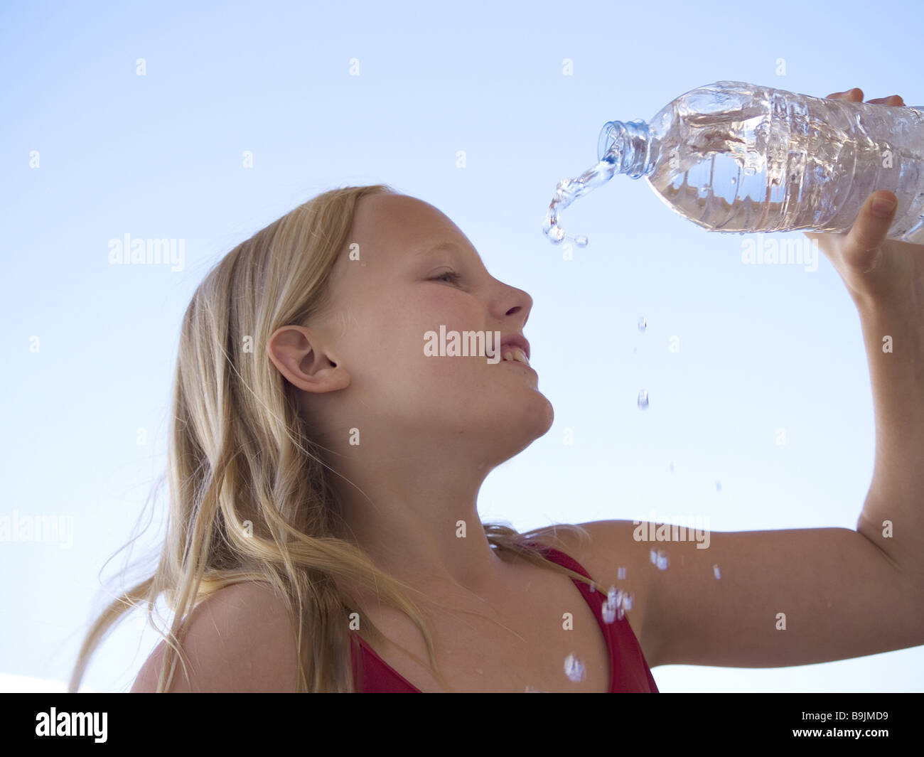 girl hand hold bottle water face pours smiling portrait series child blond long-haired profile sidewards water-bottle drinking Stock Photo