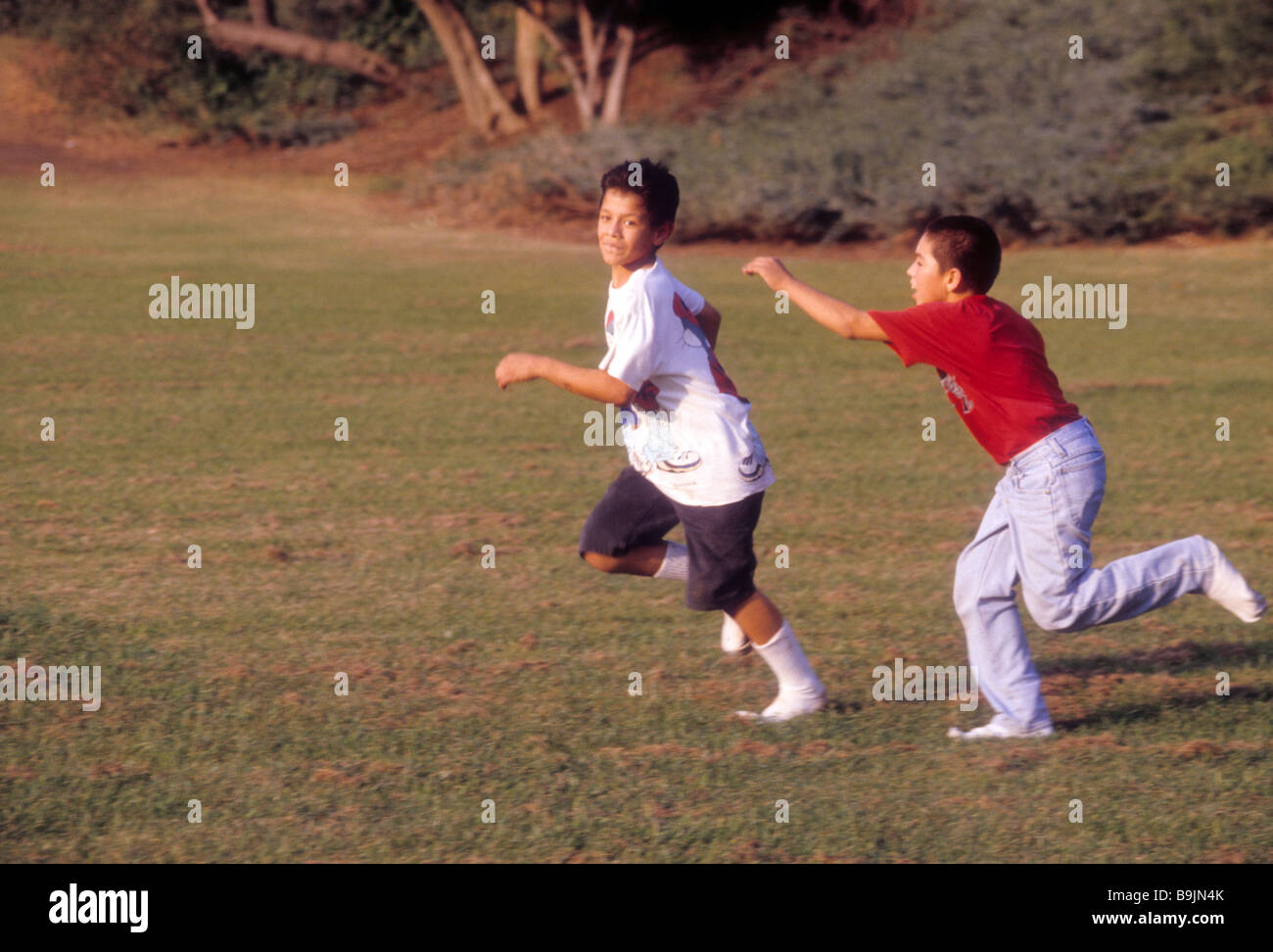 Two Hispanic boy chase tag run play park grass enjoy fun exercise sport