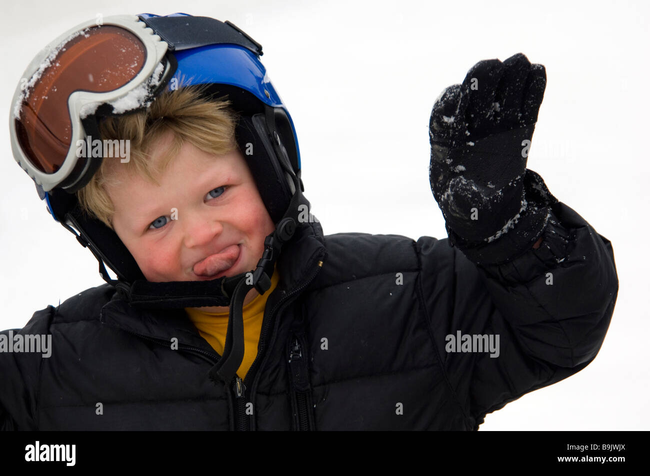 A 4yearold boy in a ski helmet and goggles smiles and plays Stock
