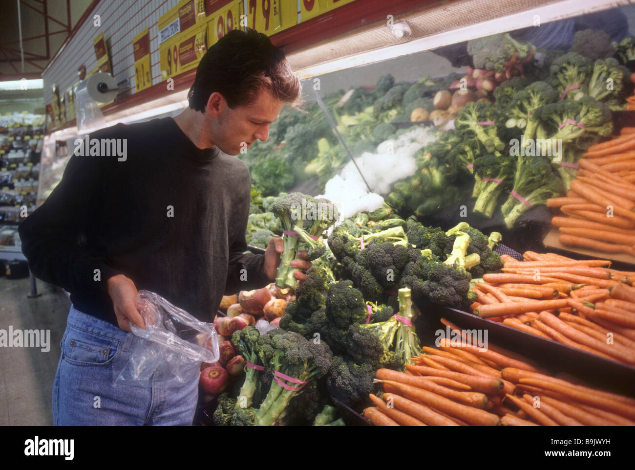 Teen boy select choose decide buy purchase fresh vegetable market store grocery food health wise smart Stock Photo