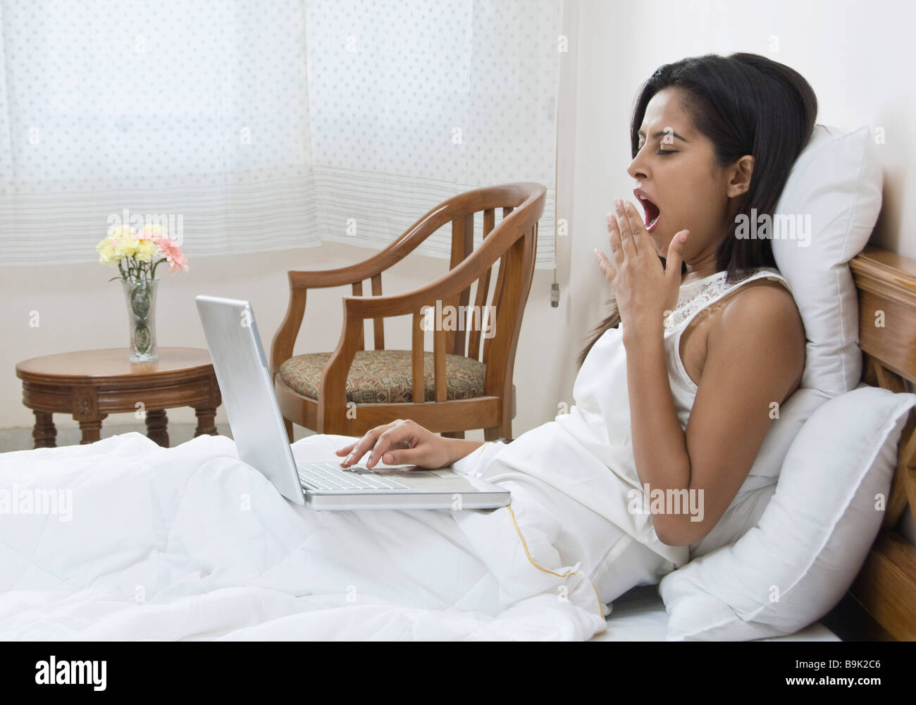Woman using a laptop on the bed Stock Photo Alamy