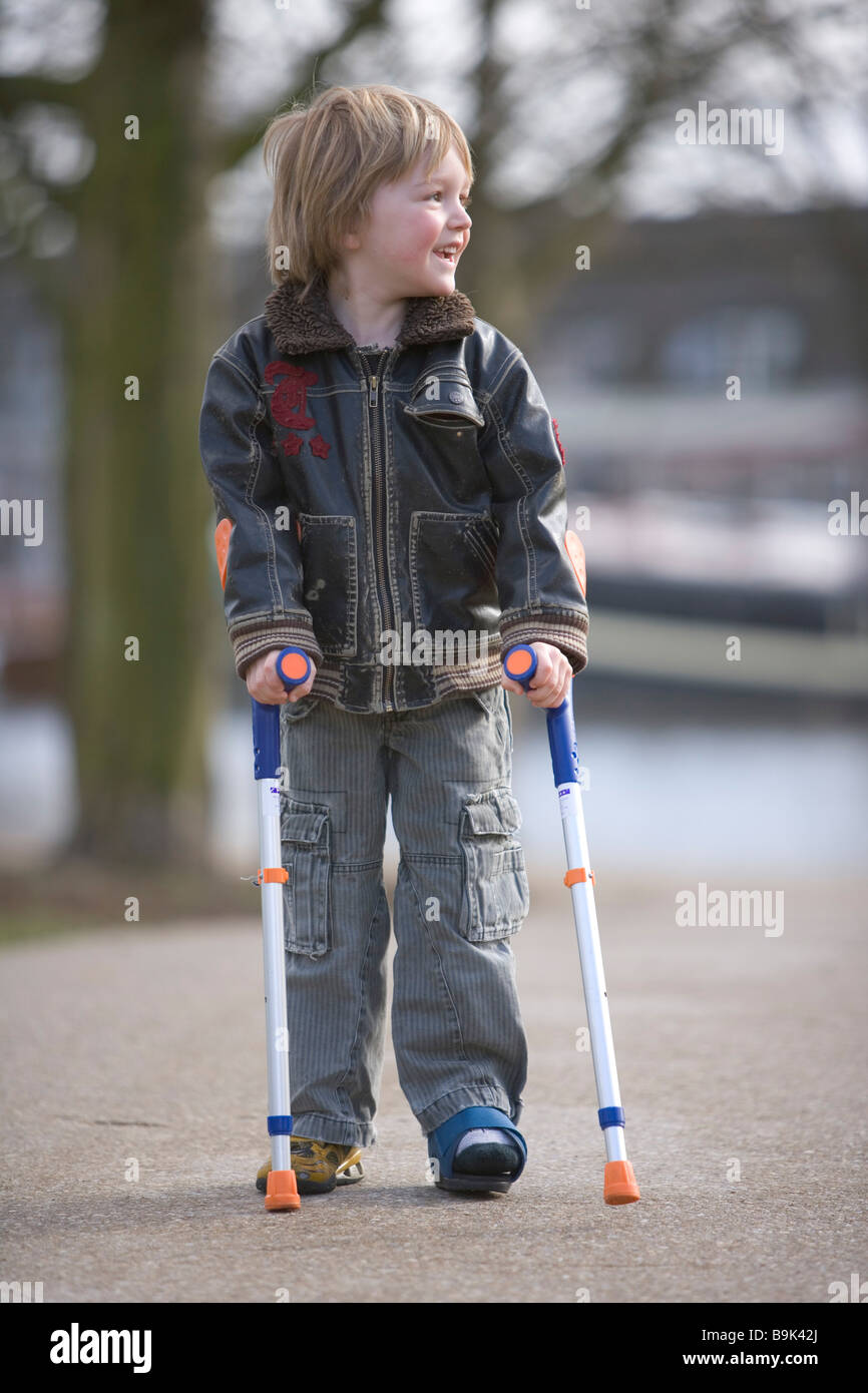 Little boy with a broken leg walking with crutches Stock Photo