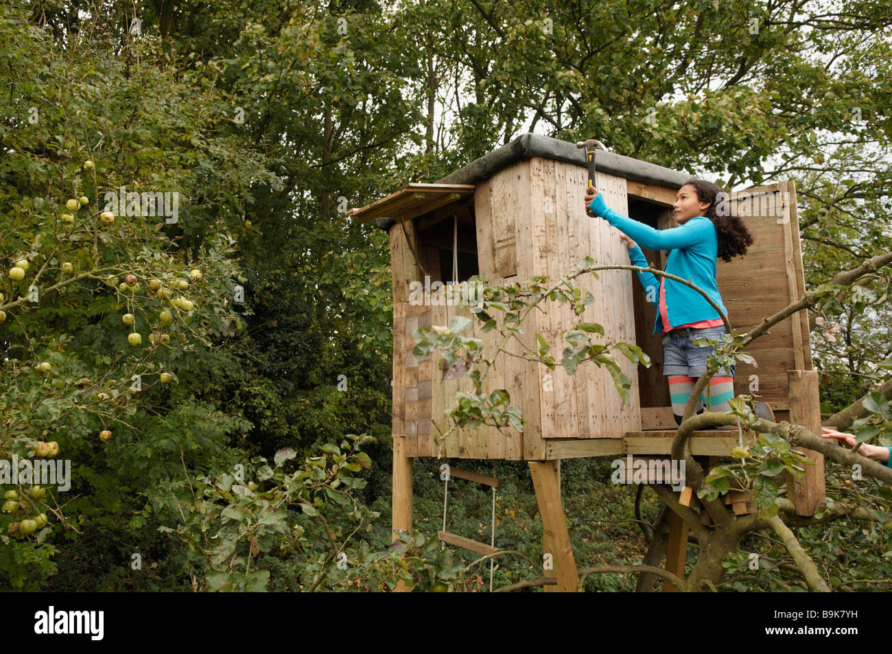Girl mending treehouse Stock Photo