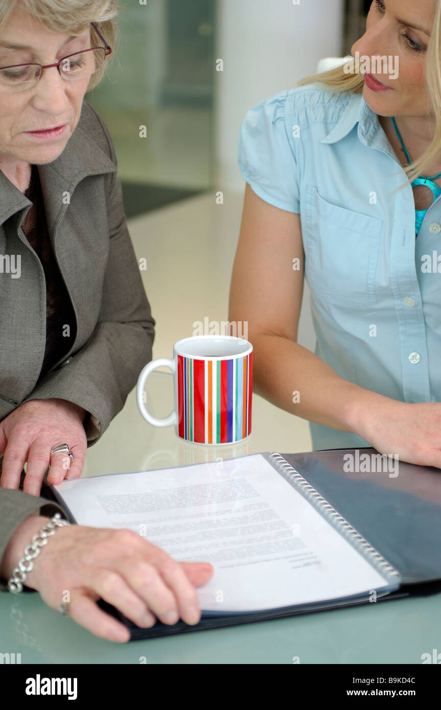 two businesswomen talking about document on table Stock Photo