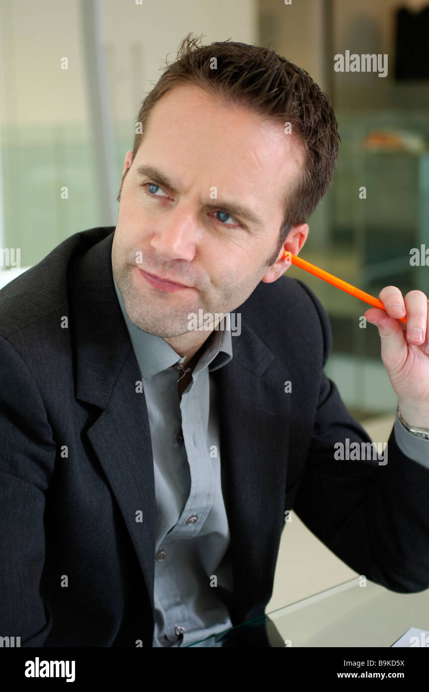businessman sticking pencil in his ear Stock Photo Alamy