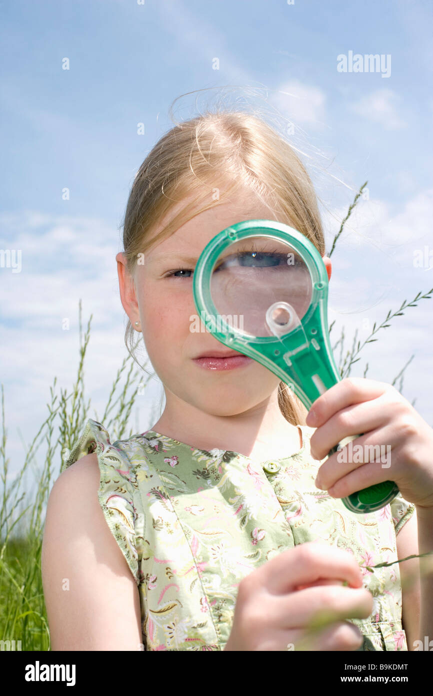 young girl looking at grass through magnifying glass Stock Photo