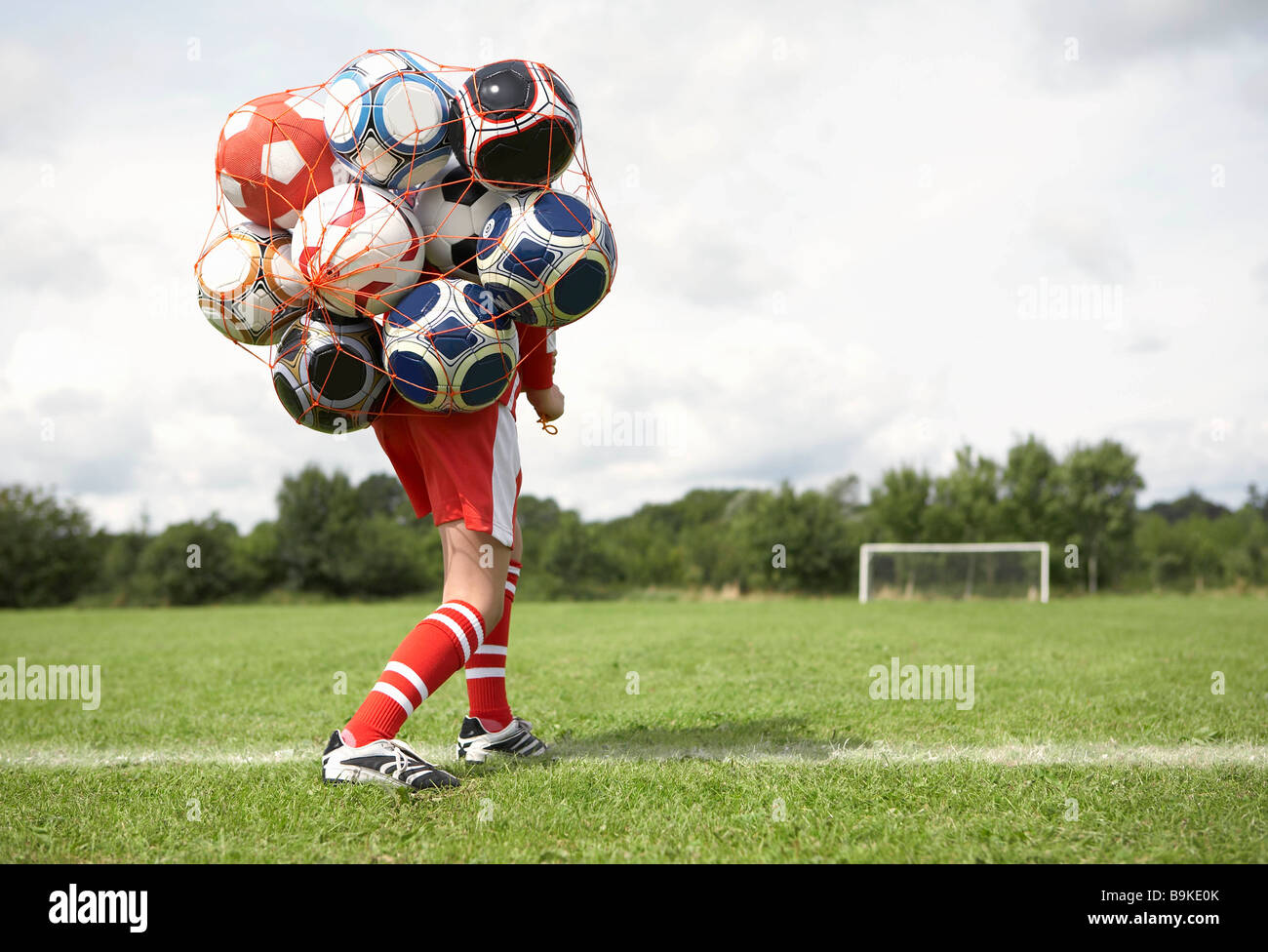 Footballer struggles with bag of balls Stock Photo