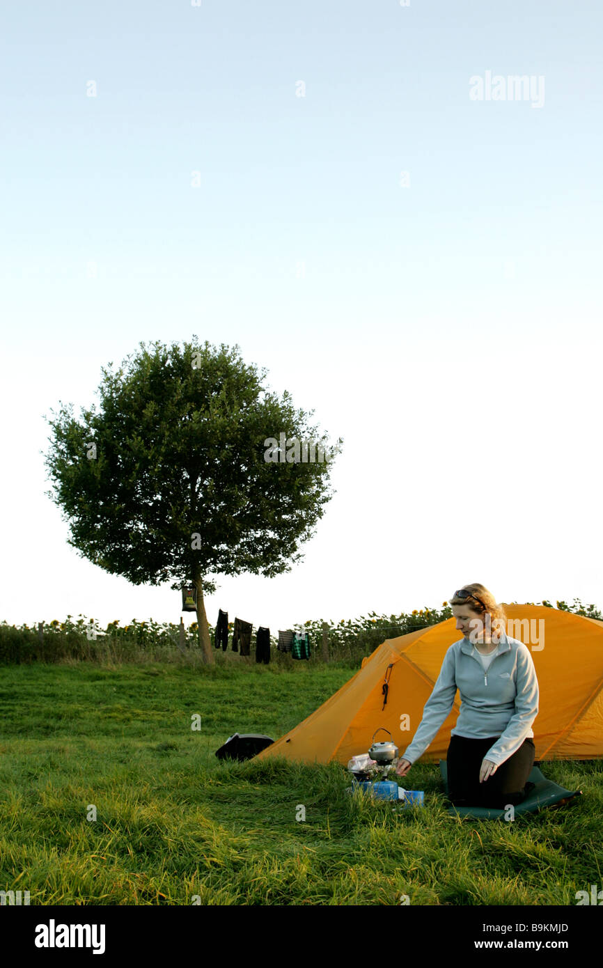 Woman cooking on camp stove outside tent with tree in the British ...