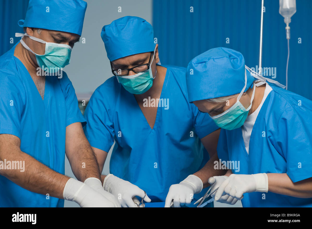 Three surgeons performing a surgery in an operating room Stock Photo