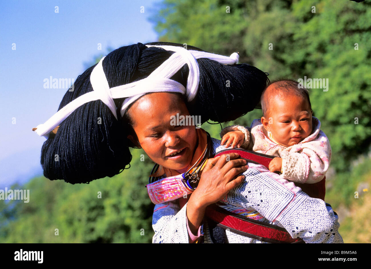 China, Guizhou province, Longhorn Miaos ethnic group woman and baby wearing wool and haircloth artificial that they reel up Stock Photo
