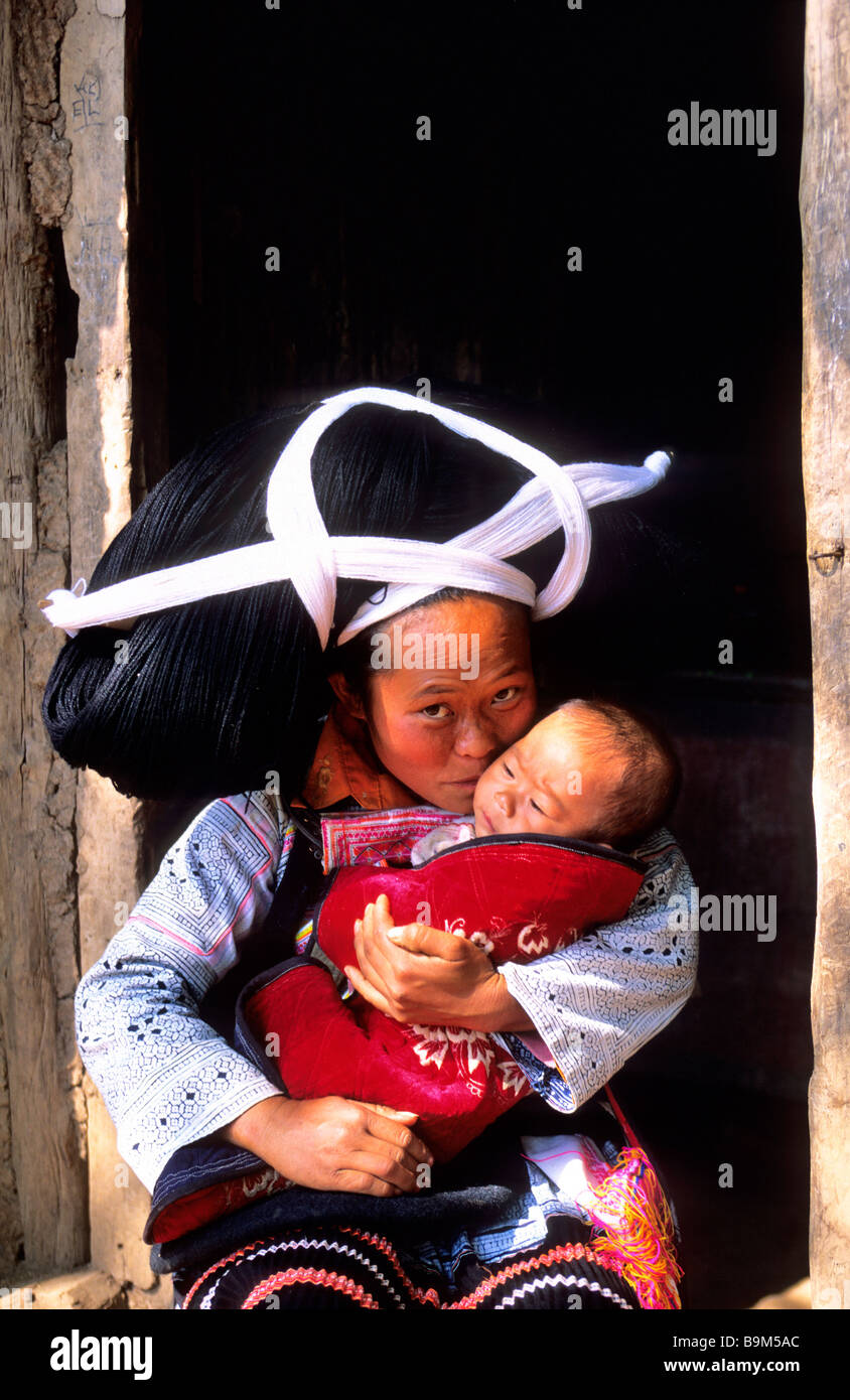 China, Guizhou province, Longhorn Miao ethnic group woman with her baby wearing wool and haircloth artificial that they reel up Stock Photo