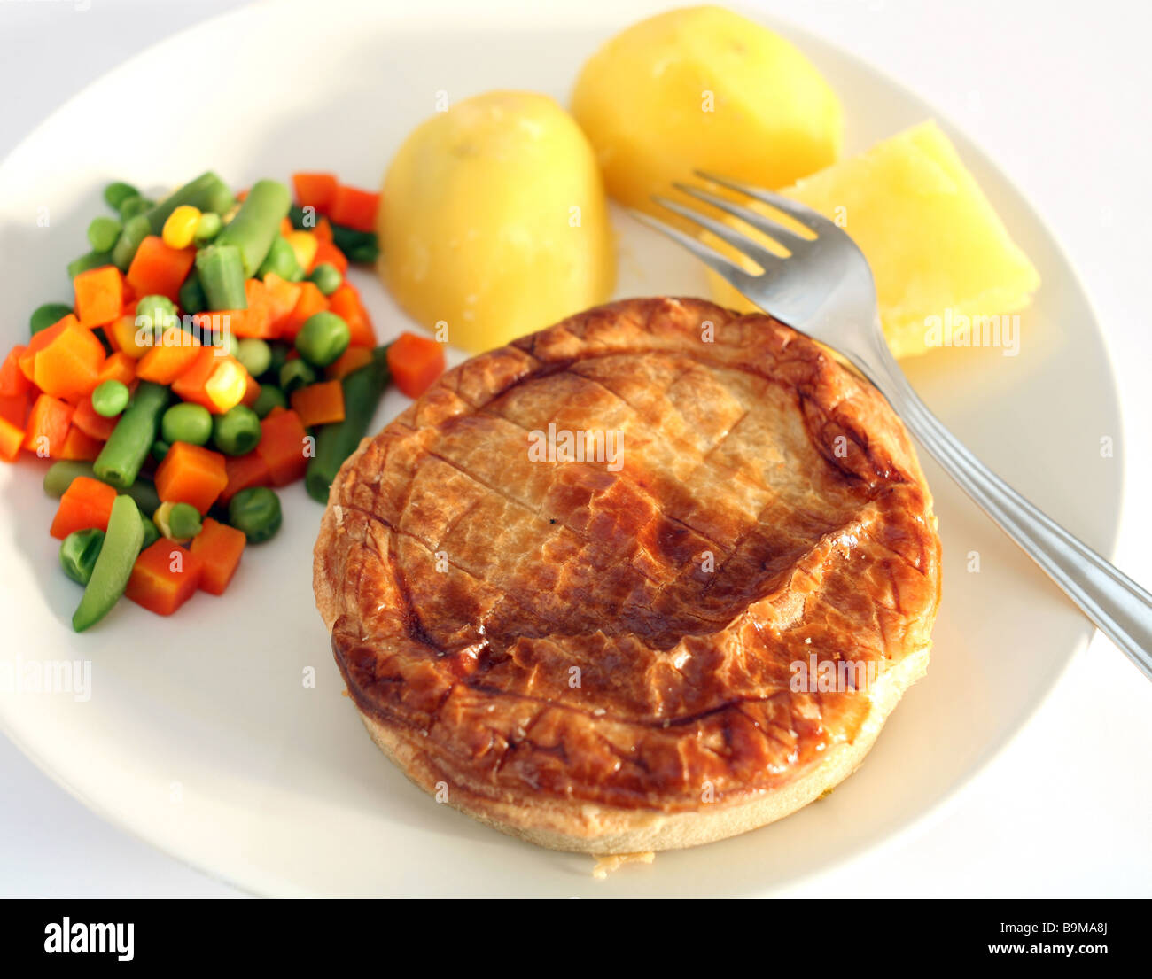 A meat pie served with boiled potatoes and mixed vegetables,shallow depth of field. Stock Photo