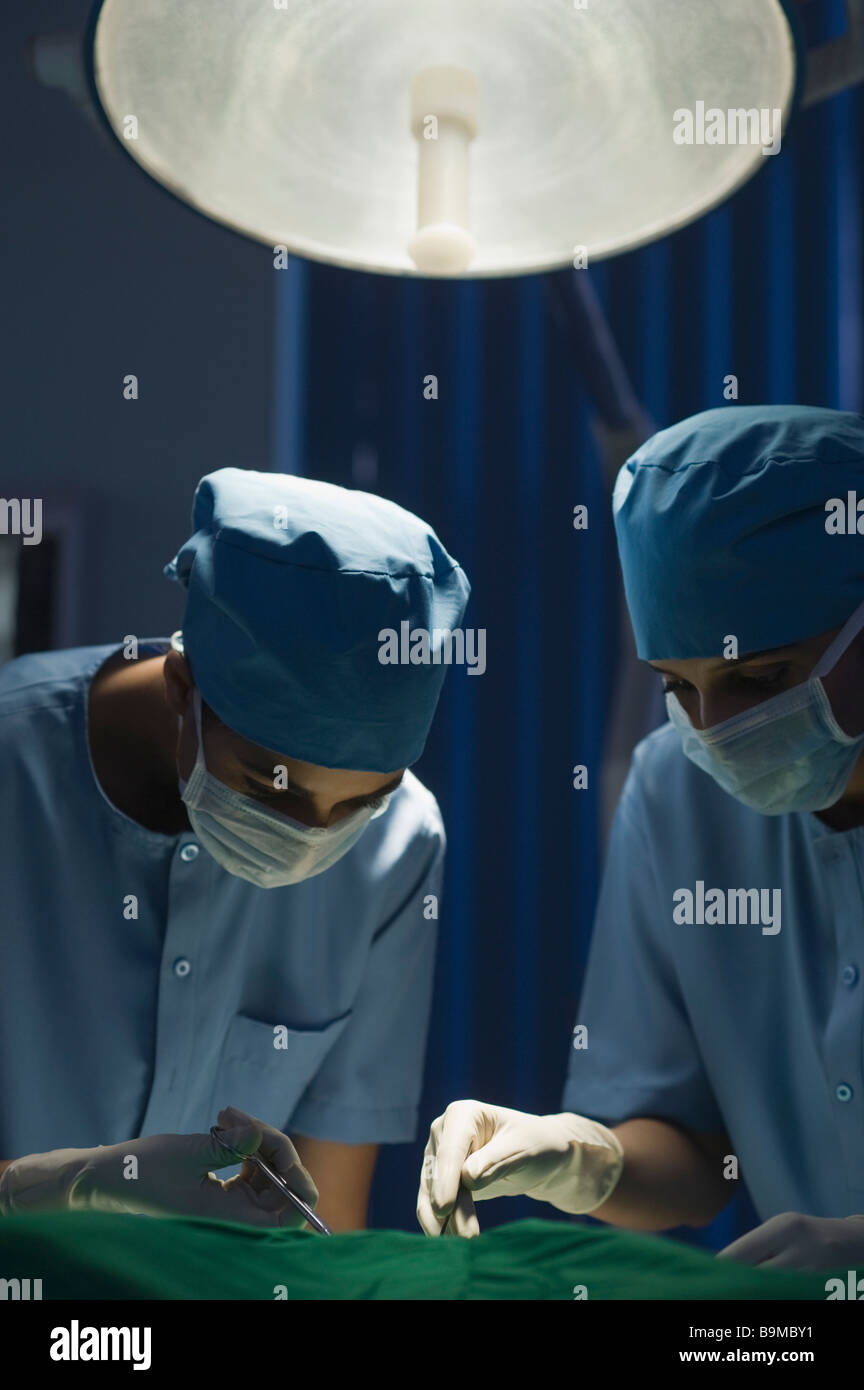 Two female surgeons performing a surgery in an operating room Stock Photo