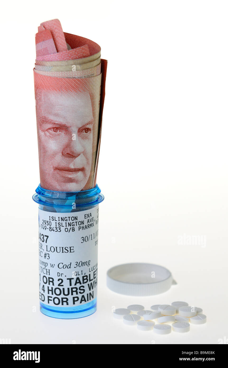 50 dollar Canadian bill in a prescription bottle for pain with pills on a white background Stock Photo